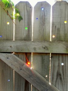 Place marbles in to holes in a fence for a sparkling light show when the sun hits the color